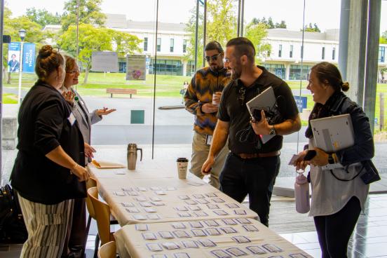 Five people standing around a table with name tags laughing